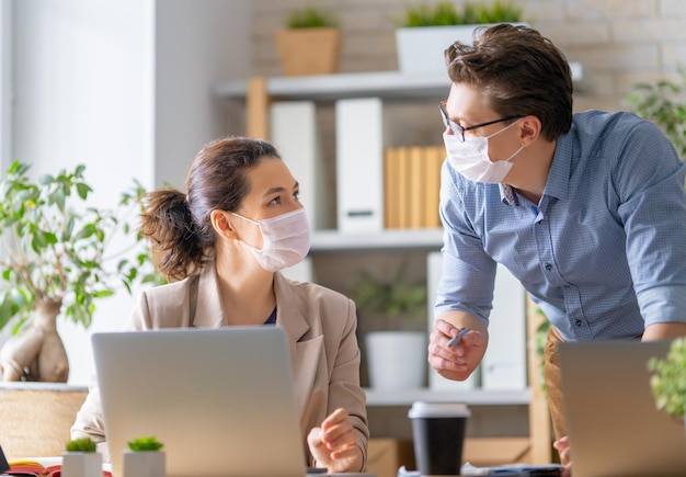 Uomo d'affari e donna d'affari con maschera medica che lavorano in ufficio. tempo di covid-19.