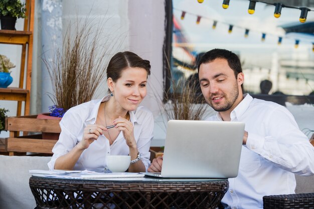 Lavoro dell'uomo d'affari e della donna di affari all'aperto al caffè della via durante il pranzo