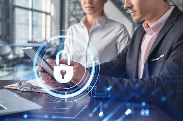 Businessman and businesswoman working together to protect\
clients confidential information and cyber security it hologram\
padlock icons over office background with panoramic windows