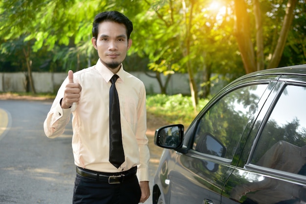 L'uomo d'affari e l'automobile hanno parcheggiato sulla via, concetto di vendita di assicurazione