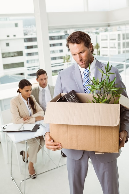 Businessman carrying his belongings in box