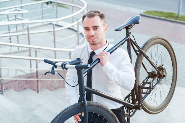 彼の自転車を運ぶビジネスマンは二階に行く