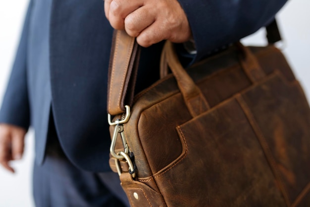 Uomo d'affari che porta la sua borsa da lavoro in pelle marrone