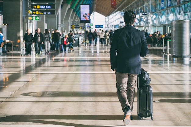 Businessman carrying suitcase while walking through a passenger departure terminal