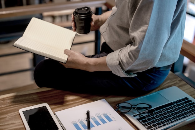 Businessman in casual style working sitting at the edge of the table