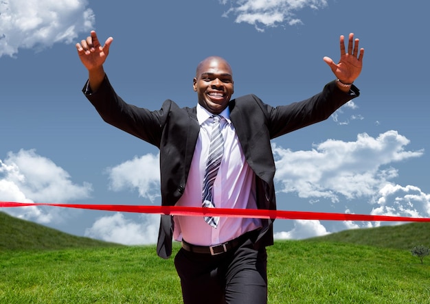 Businessman celebrating at finish line against green landscape