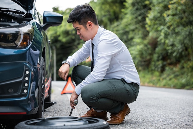 Businessman changing a flat tire