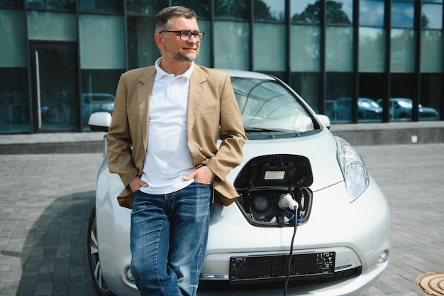 A businessman charges an electric car