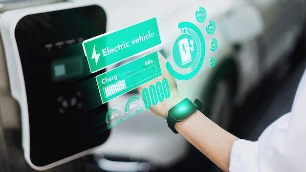 Businessman check EV car battery status on smartwatch hologram while recharge from charging station city car park Futuristic lifestyle of clean energy for EV tech adaptation Peruse