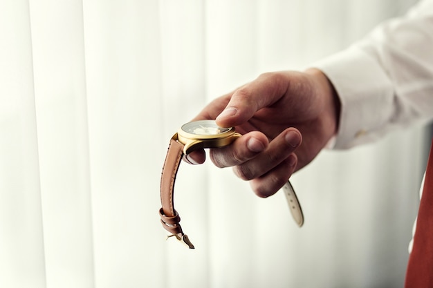 Businessman checking time on his wrist watch, man putting clock on hand,groom getting ready in the morning before wedding ceremony