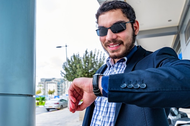 Businessman checking a wrist watch on his hand at street