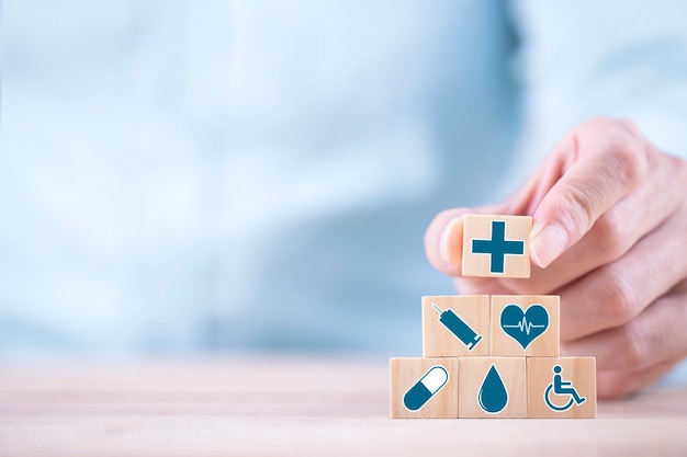 Photo businessman chooses a emoticon icons healthcare medical symbol on wooden block , healthcare and medical insurance concept