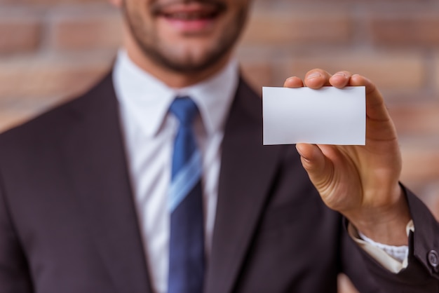 Businessman in classical suit holding a white card.