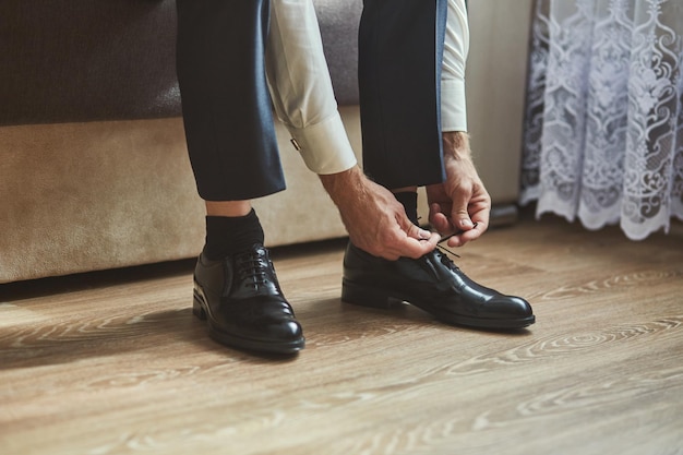 Foto uomo d'affari vestiti scarpe uomo che si prepara per lo sposo mattina prima della cerimonia di nozze