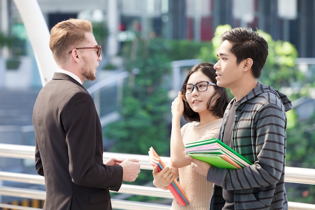 Photo businessman and college students discussing education