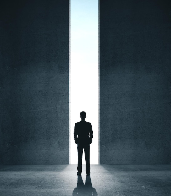 Businessman in concrete room with open door