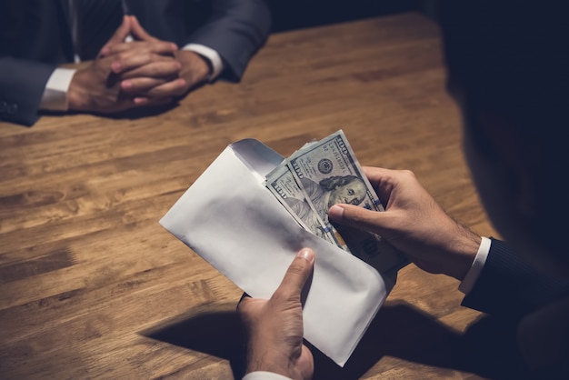 Businessman counting money in the envelope just given by his partner