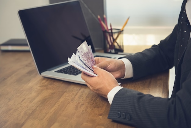 Businessman counting money, Euro bills, at his working desk