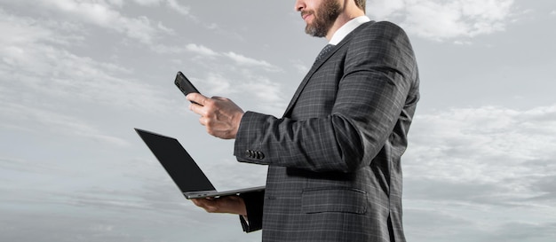 Businessman crop view using mobile phone holding laptop computer Mobile business communication Using mobile Internet for running business online Mobile technology for business