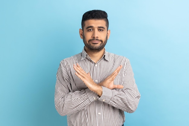 Businessman crossing hands showing x gesture rejecting bullying abuse seriously looking at camera