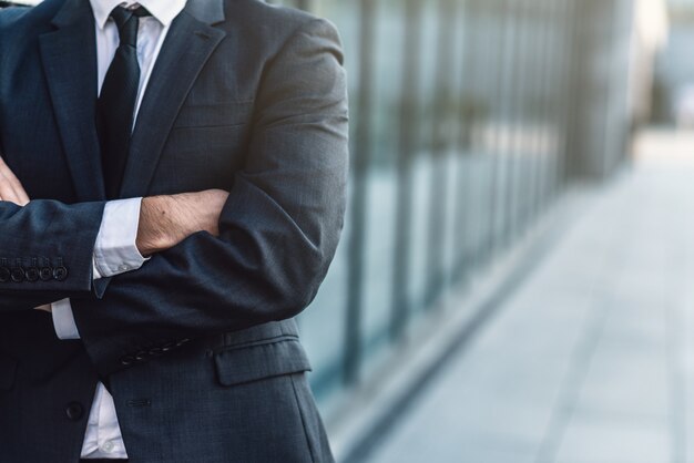 Businessman  crossing his hands posing on background of office building 