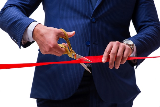 Businessman cutting red ribbon isolated on white