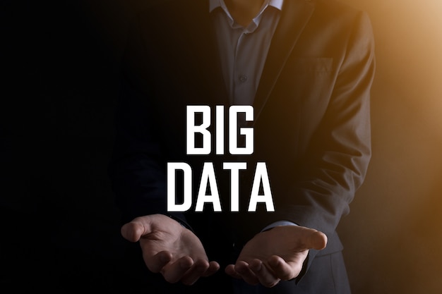 Businessman on a dark background holds the inscription BIG DATA.Storage Network Online Server