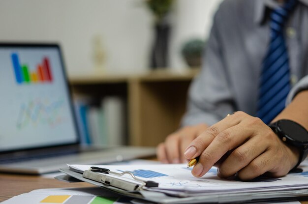 Uomo d'affari documento dati grafico grafico rapporto sviluppo ricerca di marketing lavorando in ufficio con il computer portatile