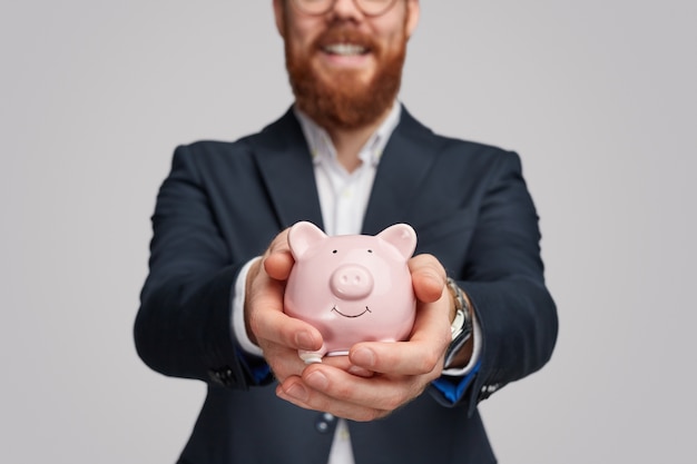 businessman demonstrating piggy bank with savings