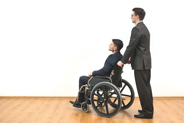 The businessman and a disabled stand on the white wall background