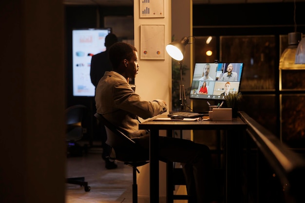 Businessman discussing marketing strategy with remote team during videocall meeting conferece. Entrepreneur working overhours at company profit progress, planning report with coworkers