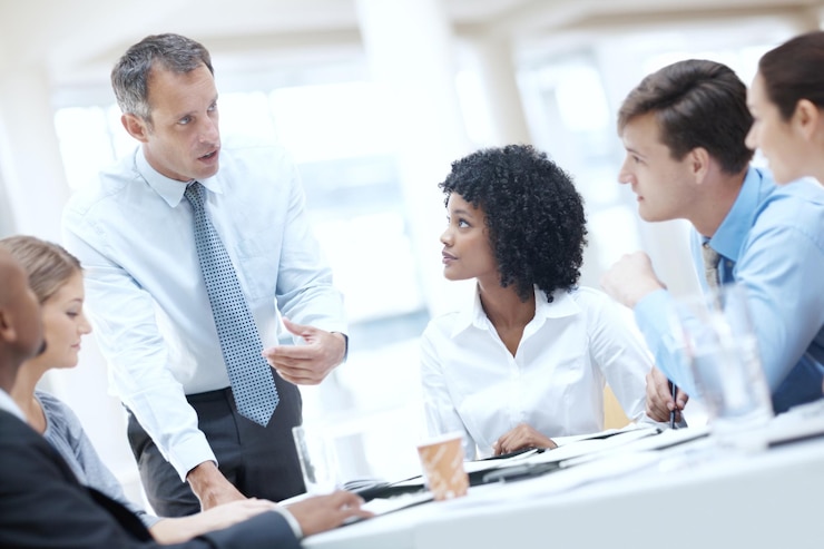 Photo businessman documents and discussion with team for meeting corporate plan or project at office man executive or speaker talking to group of employees for business improvement or development