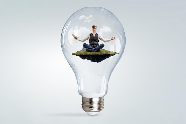 Businessman doing yoga in lotus pose inside light bulb