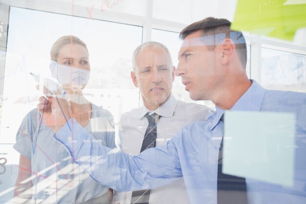 Businessman drawing graph on the glass