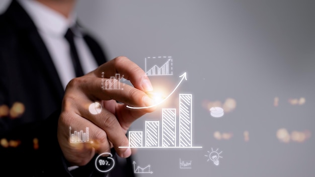 Businessman draws an increasing trend arrow and a rising chart from plan to goal It is a representation of the idea of corporate investment development