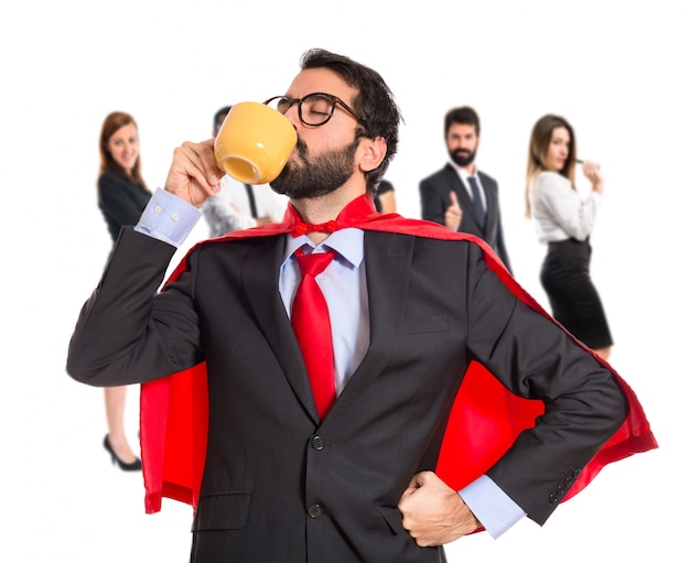 Businessman dressed like superhero drinking coffee