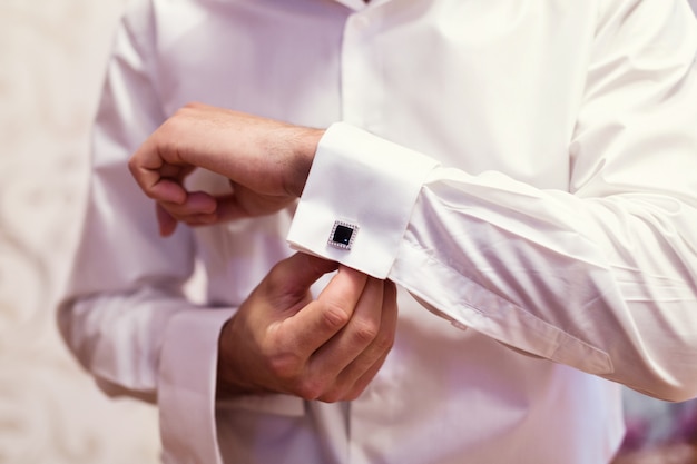 Businessman dresses white shirt, male hands closeup,groom getting ready in the morning before wedding ceremony,