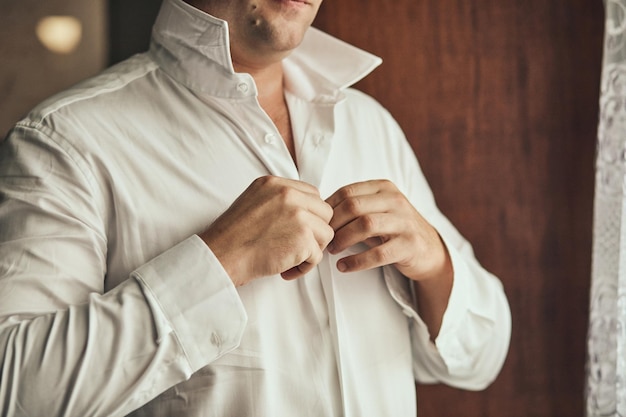 Businessman dresses white shirt male hands closeupgroom getting ready in the morning before wedding ceremony