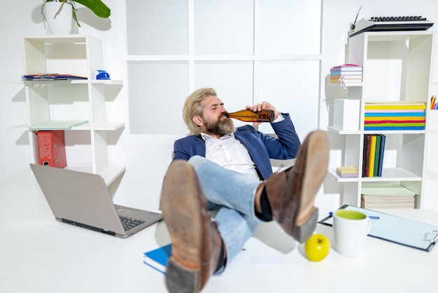 写真 ビジネスマンがオフィスでビールを広角で飲むビジネスマンがリラックスするために休憩面白い労働者お酒に夢中になる楽しいサラリーマン酔って中毒のビジネスマネージャーが椅子に座って起き上がる