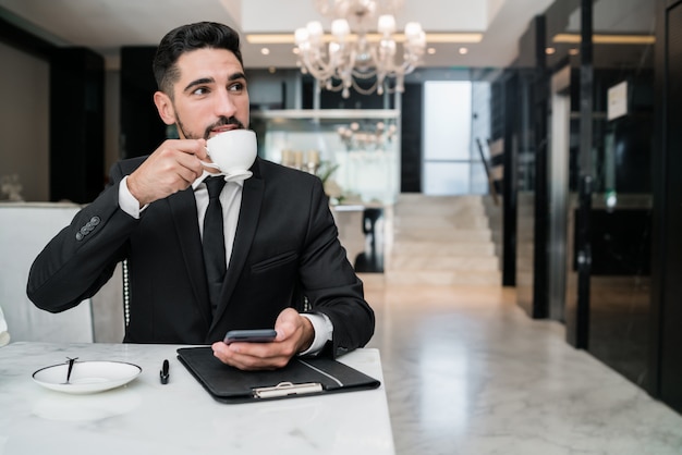 Foto uomo d'affari che beve caffè nella hall di un hotel