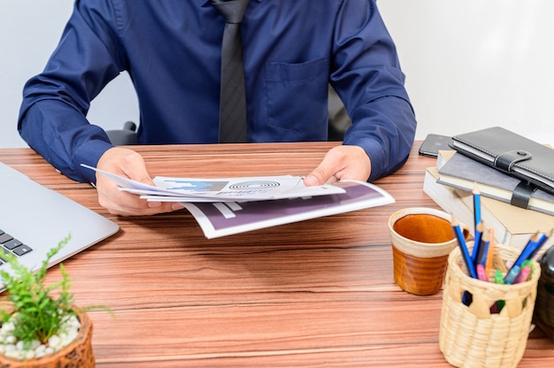 ビジネスマンは部屋の机で書類を調べます