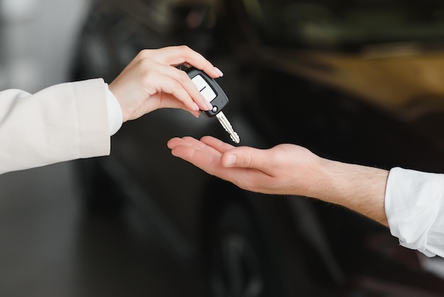 Businessman exchange handing over the car keys for to a young women