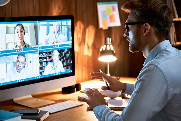 Businessman executive die virtuele teamvergaderingen leidt via videoconferentie met behulp van een computer die vanuit het kantoor thuis werkt en met verschillende collega's praat in externe videoconferenties online chat op sociale afstand