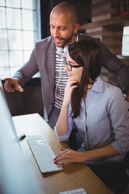 Businessman explaining female coworker over computer