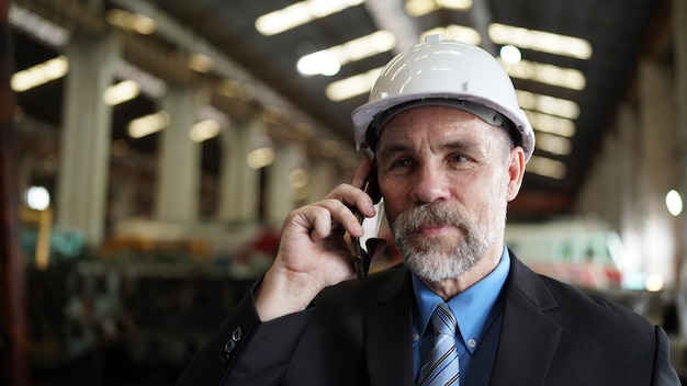 L'uomo d'affari nel magazzino della fabbrica sta parlando sul cellulare industria della fabbrica affari