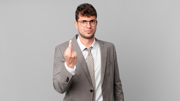 Businessman feeling angry, annoyed, rebellious and aggressive, flipping the middle finger, fighting back