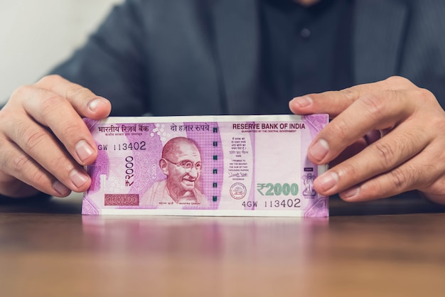 A businessman at a financial institute counting and displaying Indian Rupee banknotes