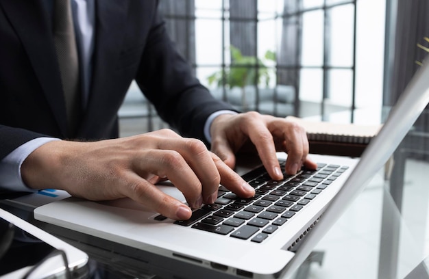 Бизнесмен печатает пальцем на клавиатуре компьютера в офисе