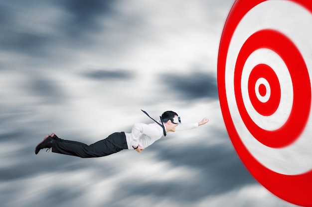 Photo businessman flying toward the target of dartboard