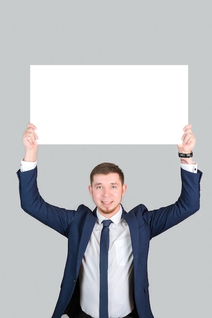 A businessman in formal attire holds a rectangular white poster mockup